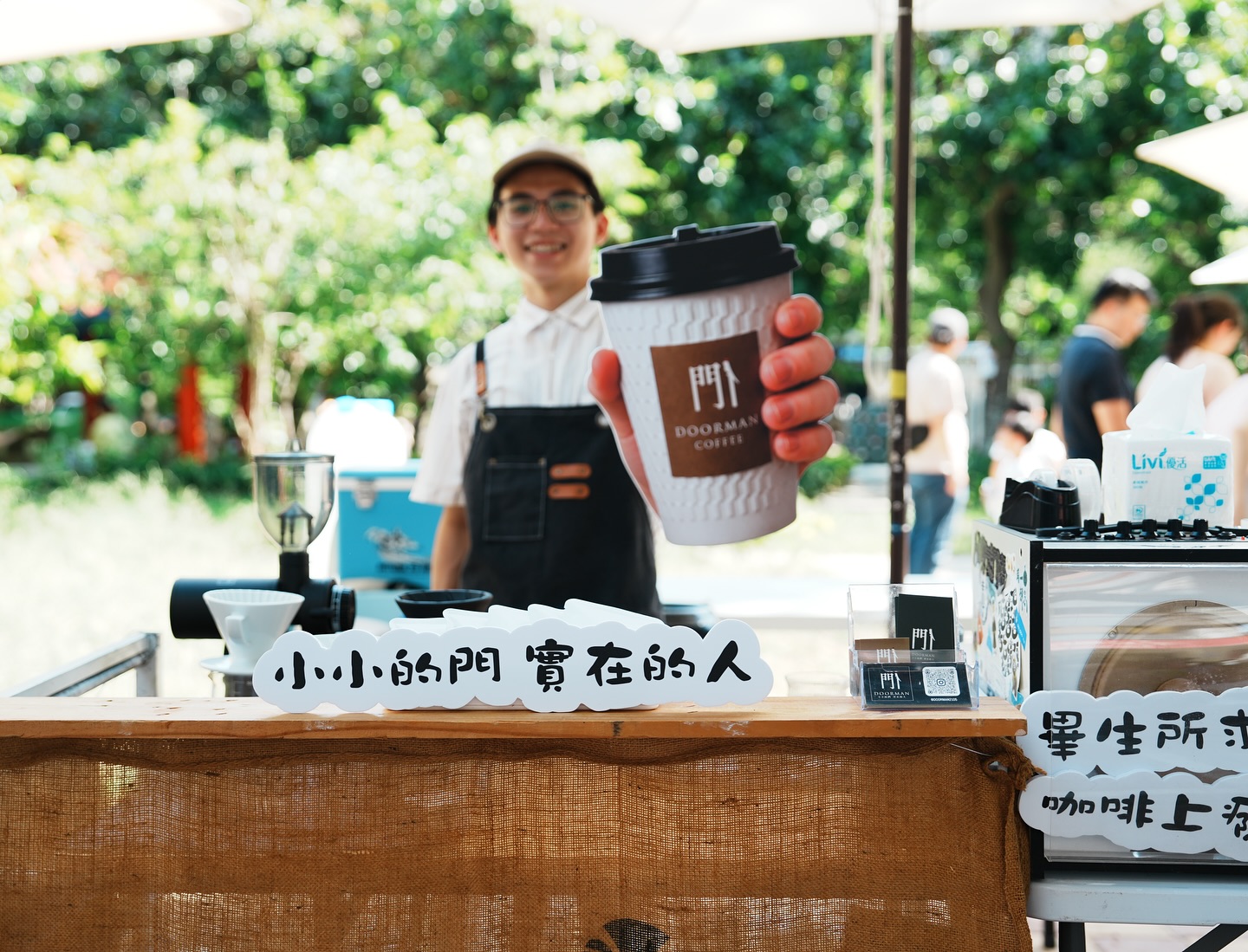 門人市集咖啡攤中遞出印有門人標誌的咖啡杯